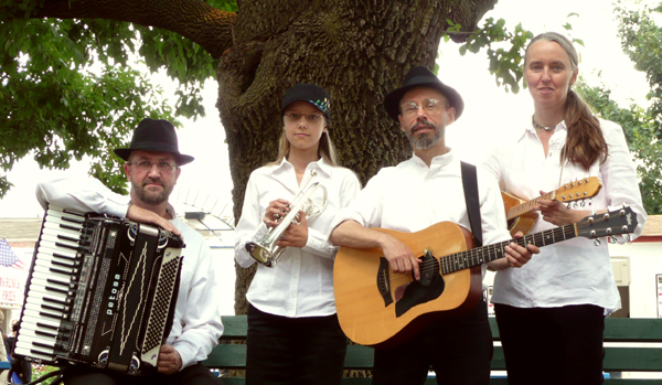 Four musicians of the Ensemble M’chaiya (tm) posing with accordion, cornet, guitar, and mandolin in front of a large tree at the Illinois State Fair in Springfield, IL. © Modal Music, Inc. (tm) All rights reserved.